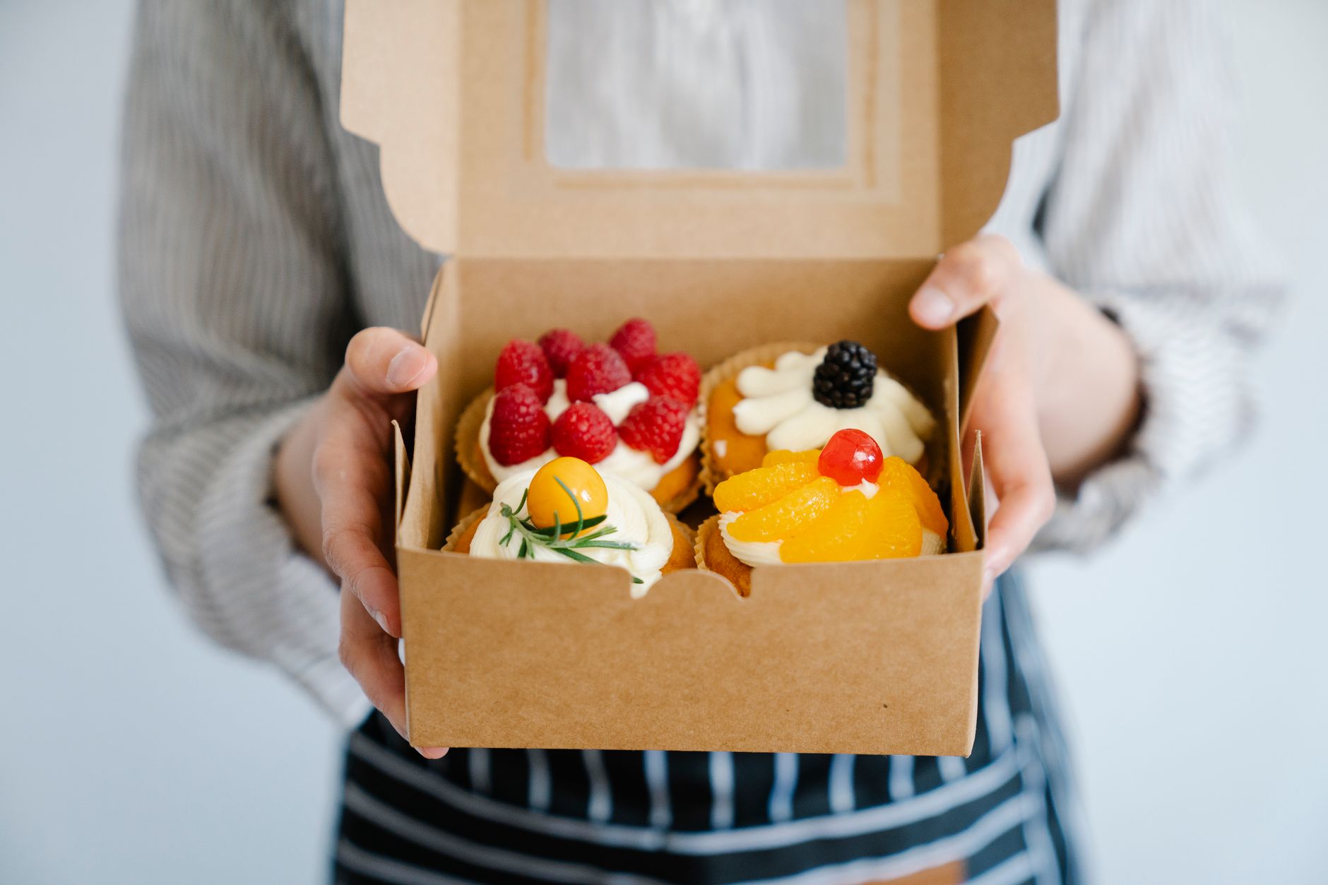 woman holding a box with fresh cupcakes